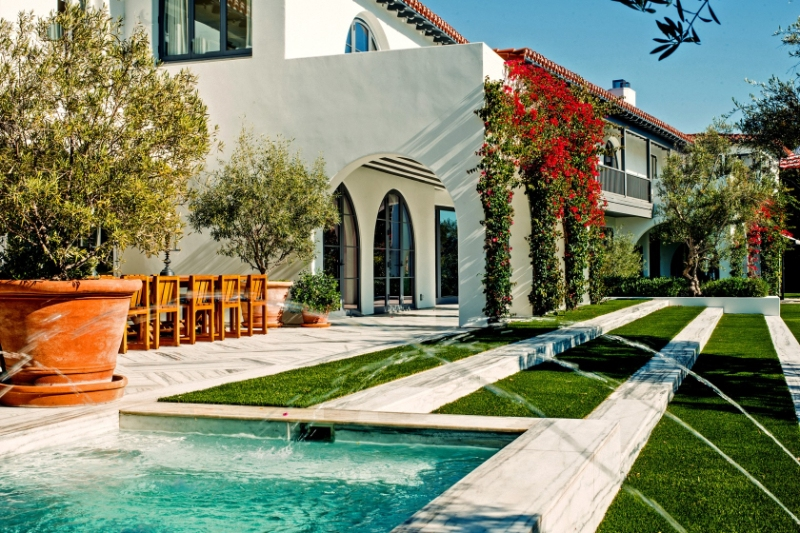 Spanish-style house with artificial grass landscaping, seamlessly extending from the fountain to the home.
