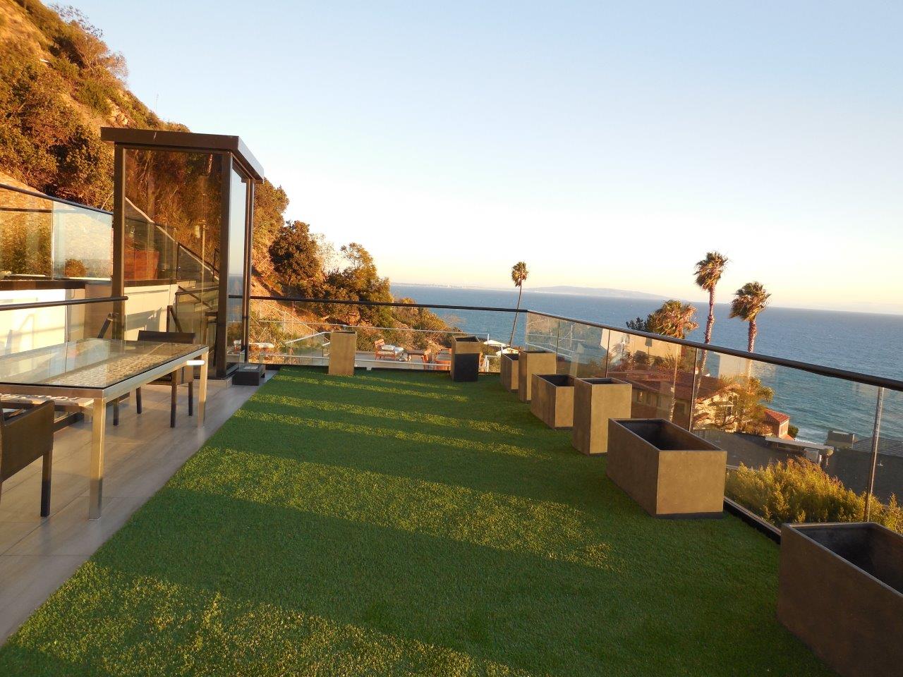 Terrace with beach views in Southern California. The terrace features a table, planters, and a lovely area with artificial turf.